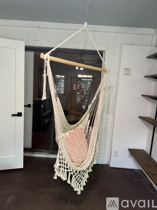 A hammock is hanging in a room with a door in the background.