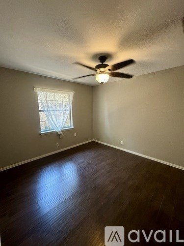 A room with a ceiling fan and a window with a view of the sky.