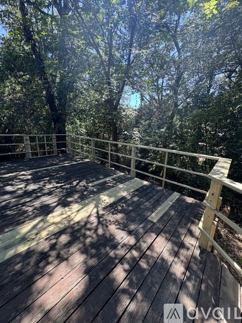 A wooden deck with railings surrounded by trees.