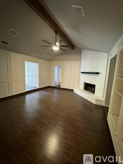 A spacious room with a fireplace and wooden flooring.