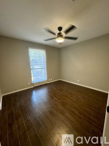 A room with a ceiling fan and wooden flooring.