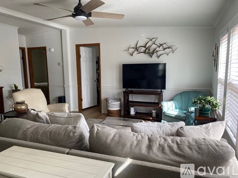 A living room with a grey couch and a television on a wooden stand.