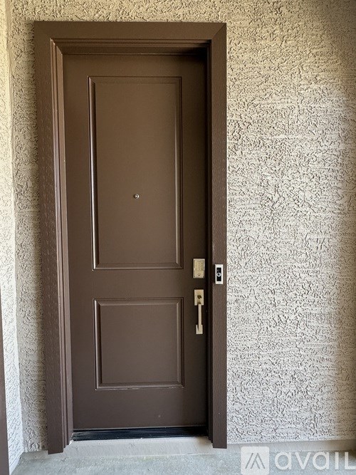 A brown door with a keyhole and a key in the lock.