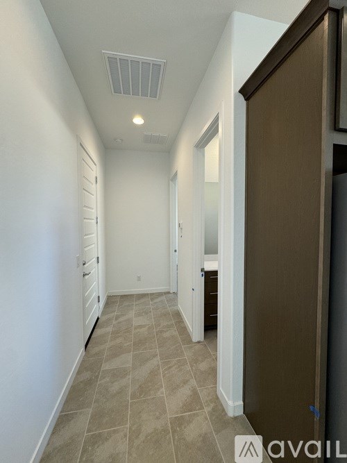 A hallway with a brown door and tiled floor.
