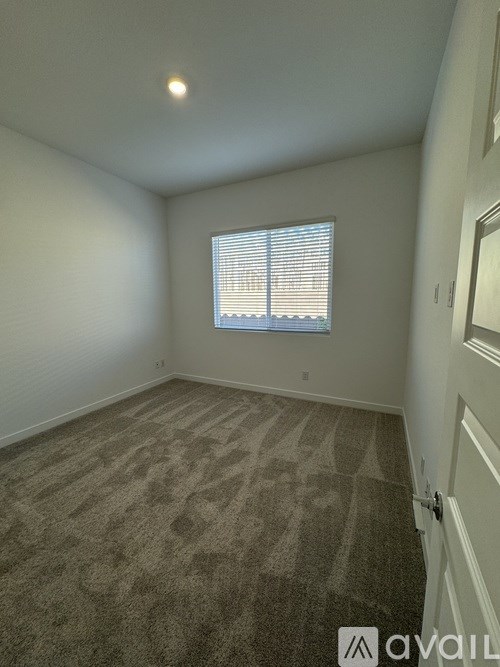 A room with carpeted floor and a window with blinds.