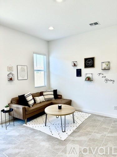 A living room with a brown couch, a coffee table, and pictures on the wall.