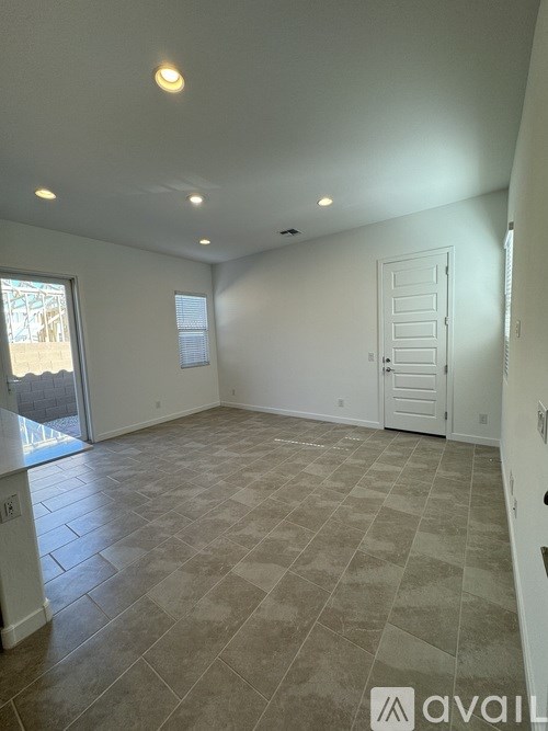 A spacious room with tiled flooring and a sliding glass door leading outside.
