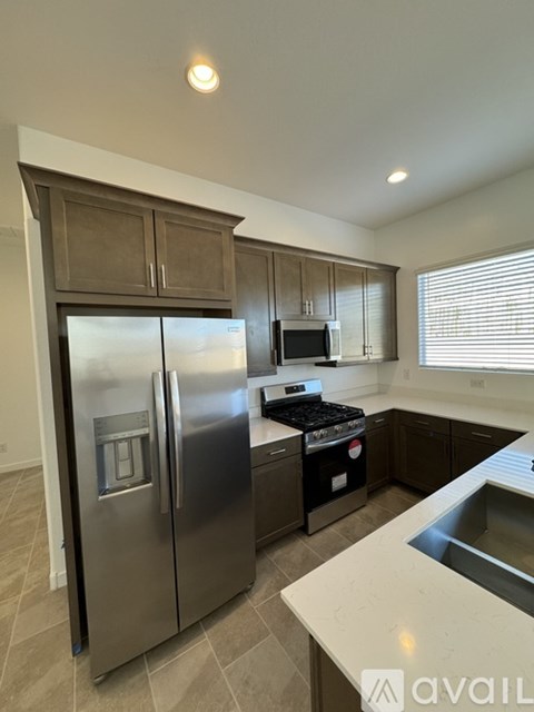 A kitchen with a stainless steel refrigerator and a stove top oven.