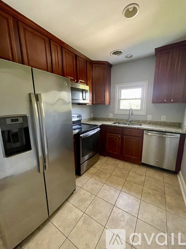 A kitchen with a refrigerator, sink, and cabinets.