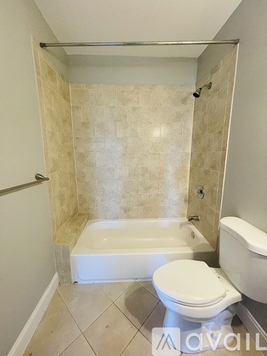 A bathroom with a toilet, tub, and tiled walls.