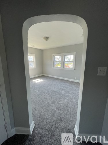 A carpeted room with a window and a door.