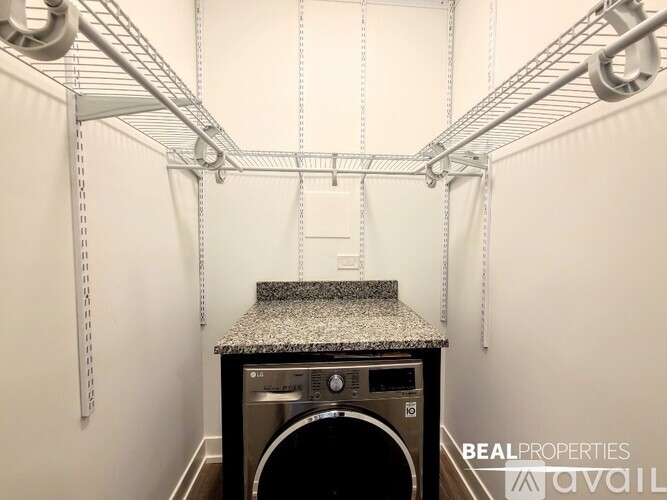 A laundry room with a washer and dryer and a shelf above.
