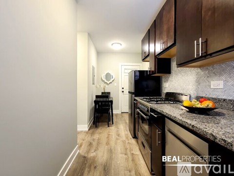 A kitchen with a black counter top and a black chair.