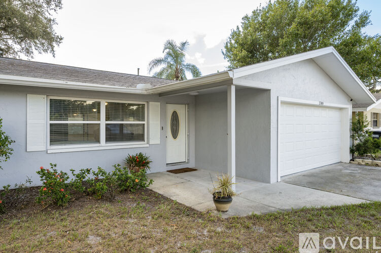 A house with a white garage door and a small front yard with a few plants.