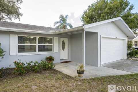 A house with a white garage door and a small front yard with a few plants.