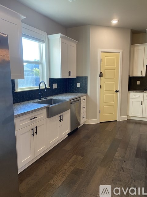 A kitchen with white cabinets and a yellow door.