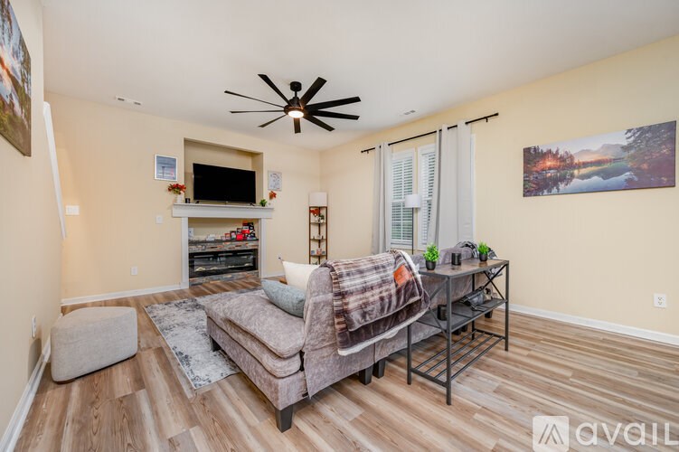 A living room with a couch, a chair, a television, and a ceiling fan.