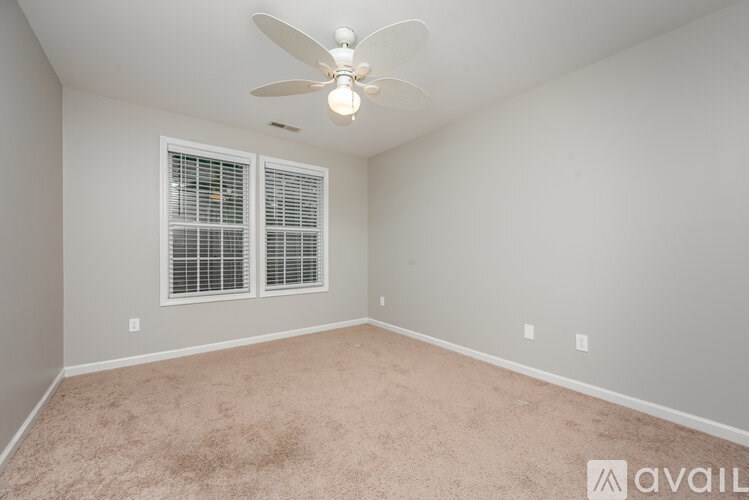 A room with a ceiling fan and carpeted floor.
