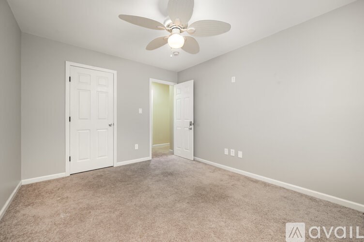 A room with a ceiling fan and carpeted floor.