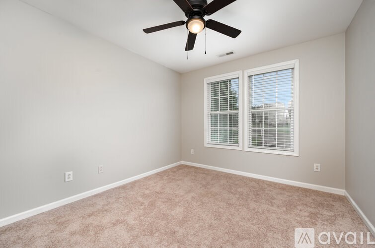 A room with a ceiling fan and carpeted floor.
