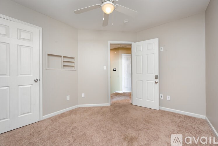 A room with a carpeted floor and a ceiling fan.