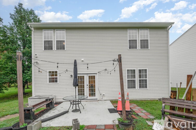 A house with a grey siding and a patio with a table and chairs.