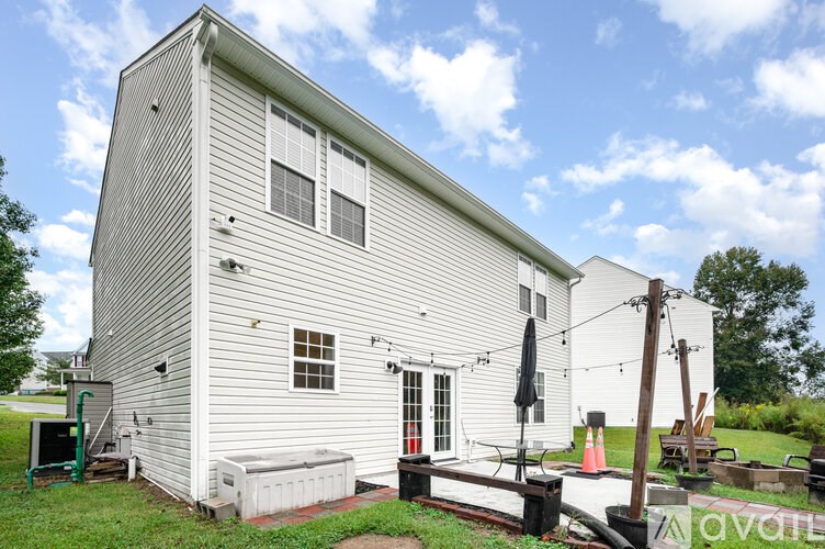 A white house with a red door and a black umbrella on the porch.
