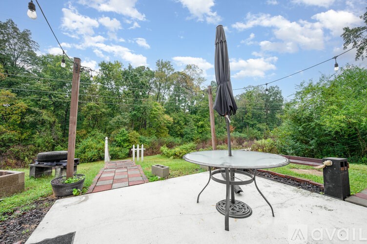 A patio with a table and chairs is surrounded by greenery.
