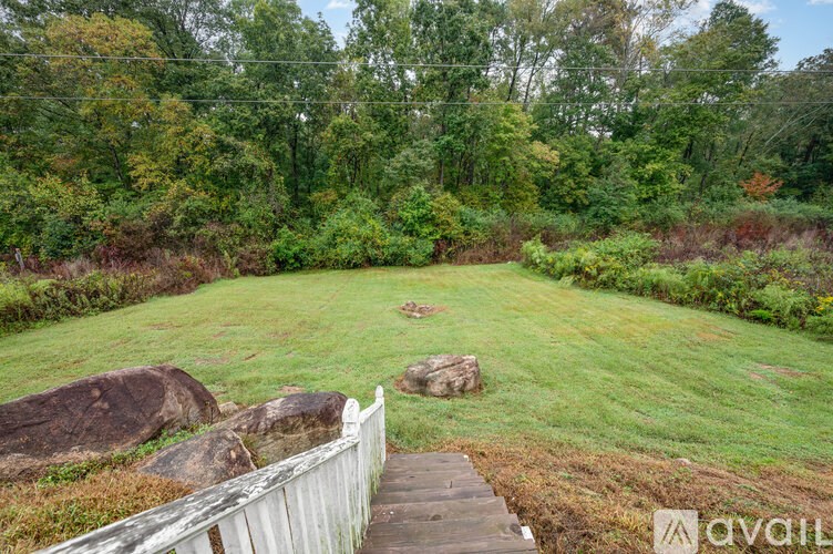 A wooden staircase leads to a grassy area with rocks and trees in the background.