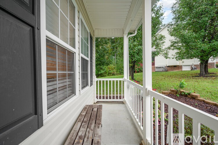 A white porch with a bench and a white railing.