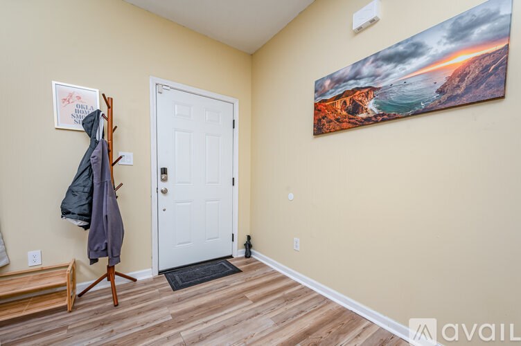 A hallway with a coat rack and a painting on the wall.