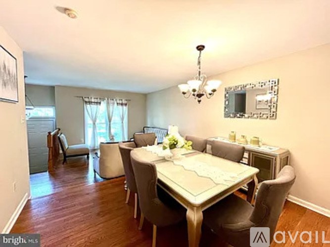 A dining room with a table set for two and chairs around it.