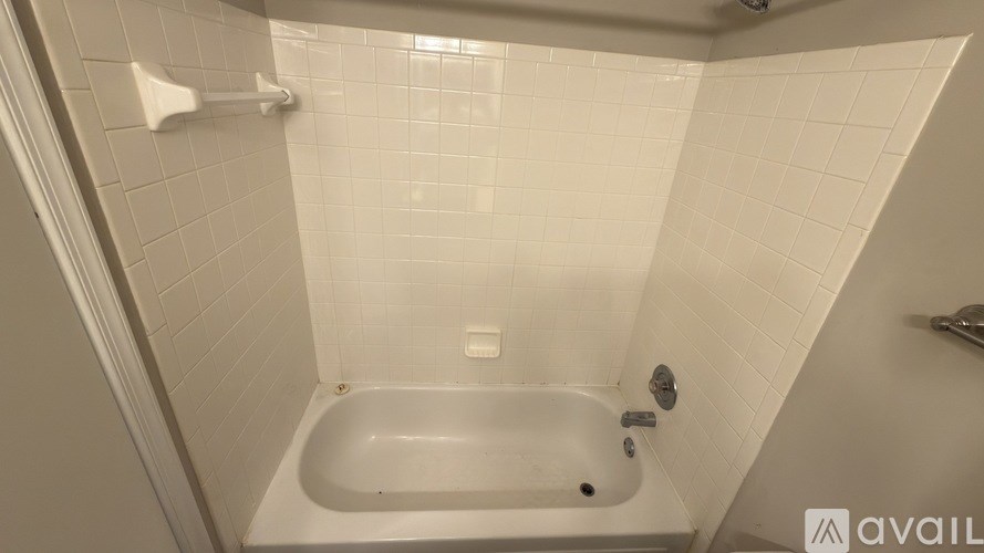 A white bathtub in a bathroom with white tiles.