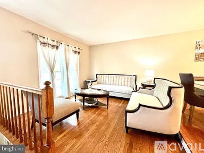A living room with a white sofa and a wooden staircase.