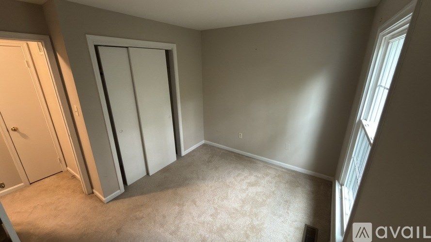 A room with a carpeted floor and a window letting in natural light.