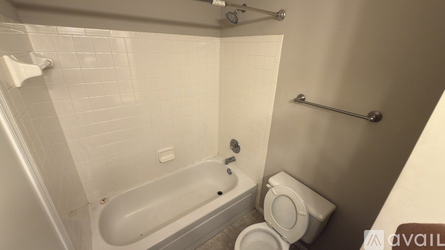 A white toilet is in a small bathroom with a white tub and a shower.