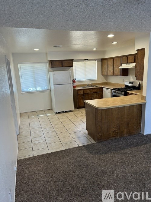A kitchen with white appliances and wooden cabinets.