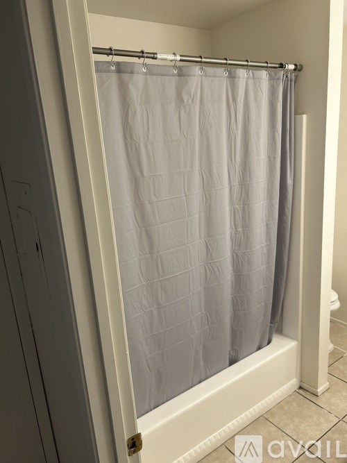 A shower curtain is hanging in a white bathroom.