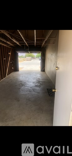 A long, empty hallway with a concrete floor and white walls.