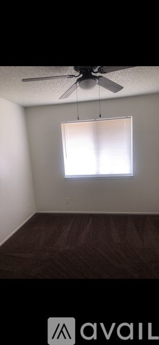A room with a ceiling fan and a window with blinds.