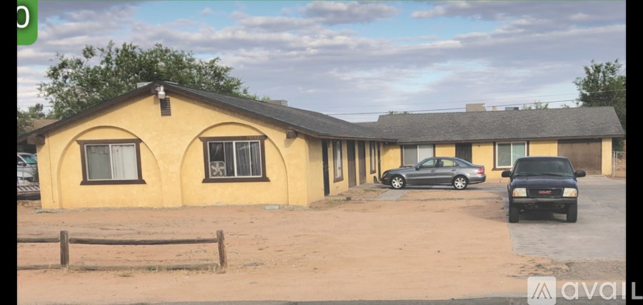 A yellow house with a black car parked in front.