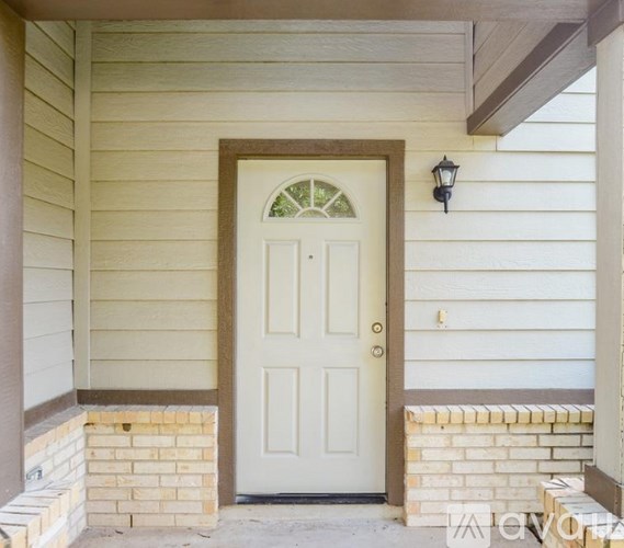 A white door with a glass window above it is set in a white siding house.