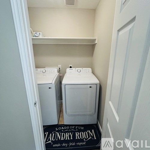 A laundry room with two washing machines and a sign on the floor.