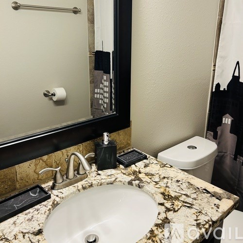 A bathroom with a marble countertop and a white sink.