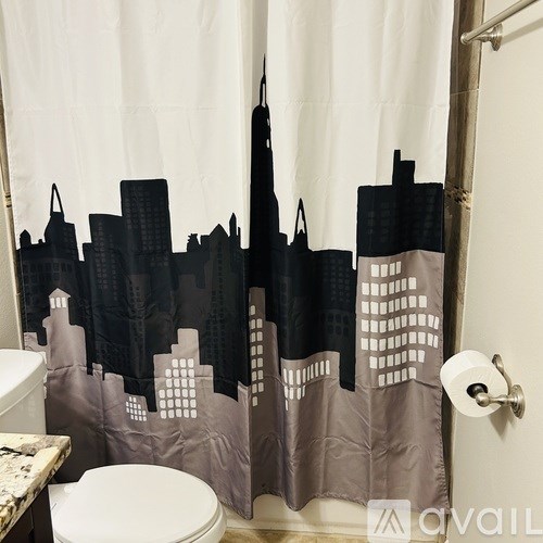 A shower curtain with a city skyline design is hanging in a bathroom.