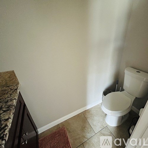 A white toilet sits in a bathroom next to a marble counter.