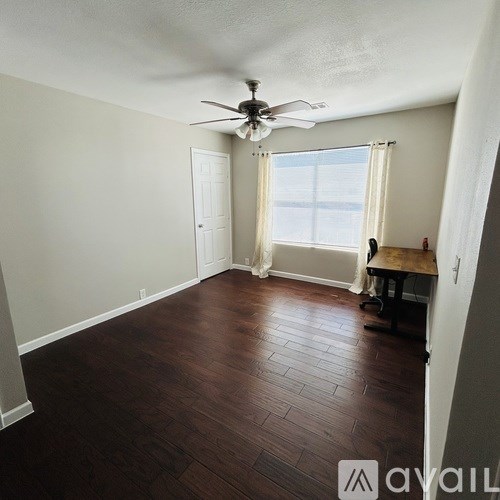 A room with a ceiling fan and wooden flooring.