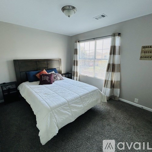 A bedroom with a large bed and a window with curtains.