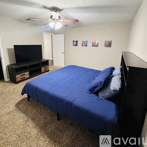 A bedroom with a blue bed and a black television.