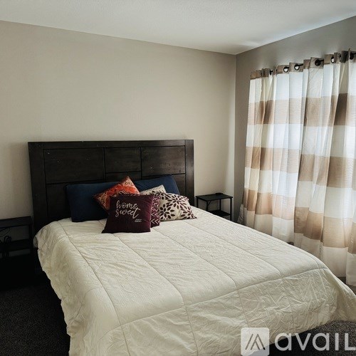 A bed with a white comforter and a wooden headboard with two pillows on it.